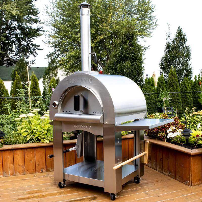 Well-designed Pinnacolo Premio Pizza Oven in a garden setting, showcasing its stainless steel build and outdoor capabilities.