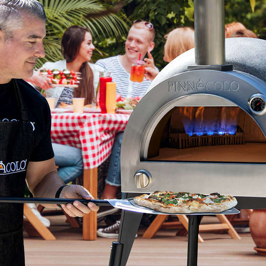 How to Cook a Perfect Pizza in an Outdoor Pizza Oven with a chef using a pizza peel in front of a pizza oven.